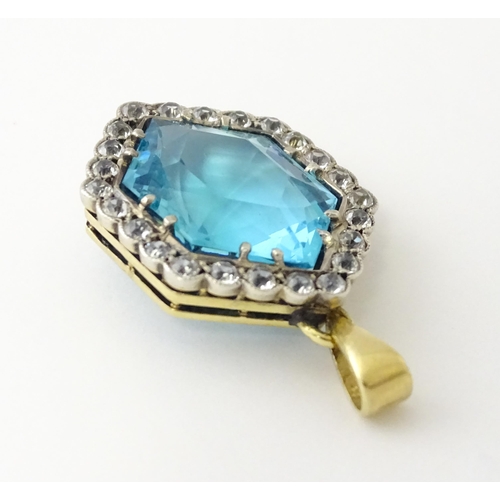 665 - A yellow metal pendant set with central blue stone bordered by white stones. Approx. 1 1/2