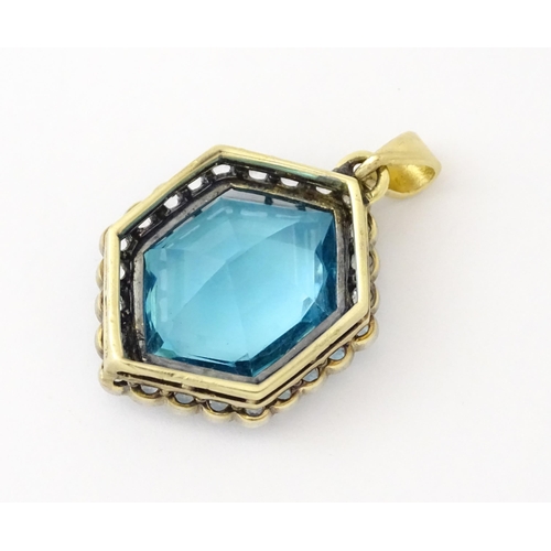 665 - A yellow metal pendant set with central blue stone bordered by white stones. Approx. 1 1/2