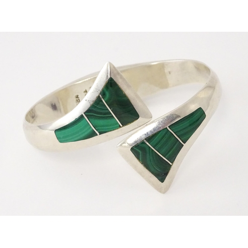 669 - A Mexican silver bracelet of bangle form set with malachite.