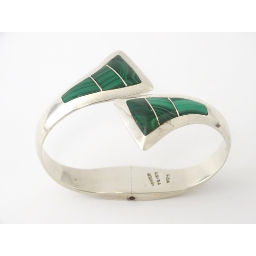 669 - A Mexican silver bracelet of bangle form set with malachite.