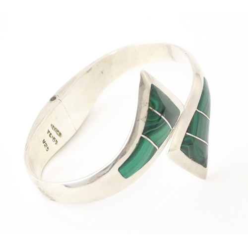 669 - A Mexican silver bracelet of bangle form set with malachite.