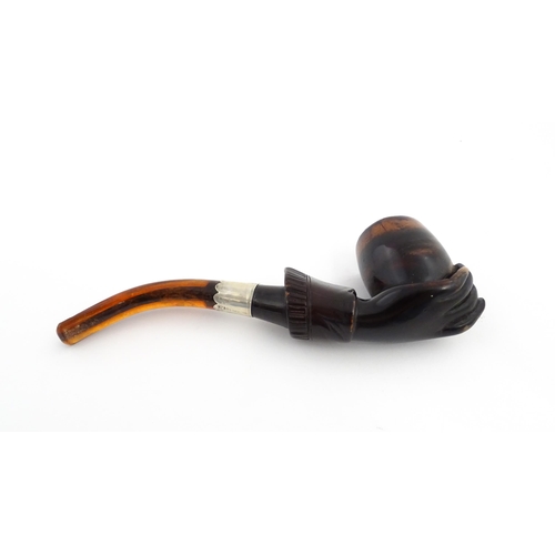 1253 - A Victorian meerschaum pipe carved as a hand with cuff holding the bowl, with amber mouthpiece and s... 