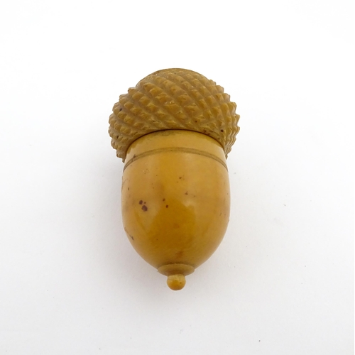 1257 - A Victorian carved coquilla nut thimble case modelled as an acorn. Containing a Victorian silver thi... 