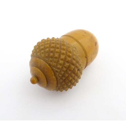 1257 - A Victorian carved coquilla nut thimble case modelled as an acorn. Containing a Victorian silver thi... 