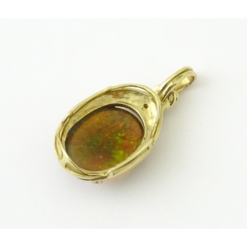 686 - A 9ct gold pendant set with opal cabochon  surmounted by a diamond. Approx 1