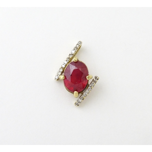 689 - A 9ct gold pendant set with central ruby flanked by bands of diamonds. Approx. 1/2