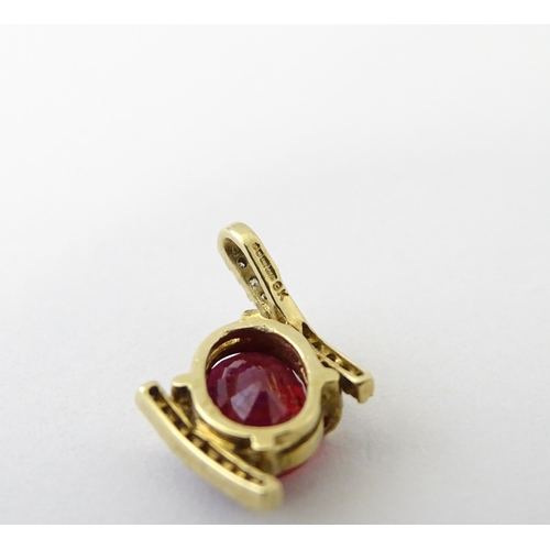 689 - A 9ct gold pendant set with central ruby flanked by bands of diamonds. Approx. 1/2