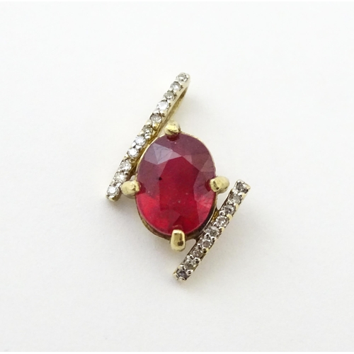 689 - A 9ct gold pendant set with central ruby flanked by bands of diamonds. Approx. 1/2