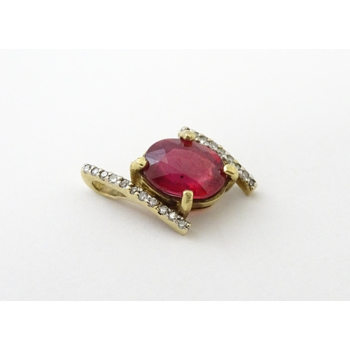 689 - A 9ct gold pendant set with central ruby flanked by bands of diamonds. Approx. 1/2