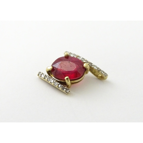 689 - A 9ct gold pendant set with central ruby flanked by bands of diamonds. Approx. 1/2