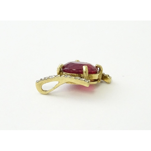 689 - A 9ct gold pendant set with central ruby flanked by bands of diamonds. Approx. 1/2