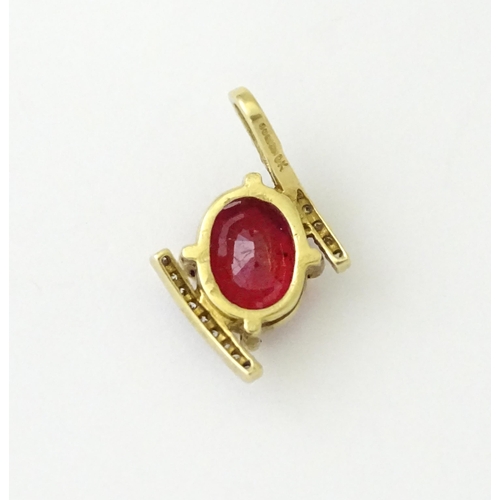 689 - A 9ct gold pendant set with central ruby flanked by bands of diamonds. Approx. 1/2