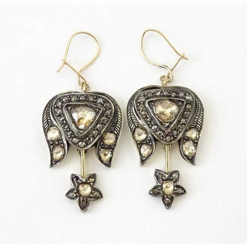 704 - A pair of yellower metal drop earrings set with a profusion of diamonds. Approx. 1 1/2