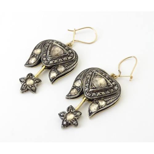 704 - A pair of yellower metal drop earrings set with a profusion of diamonds. Approx. 1 1/2