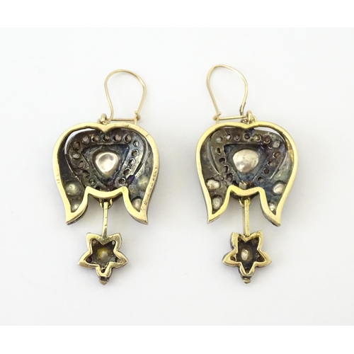 704 - A pair of yellower metal drop earrings set with a profusion of diamonds. Approx. 1 1/2