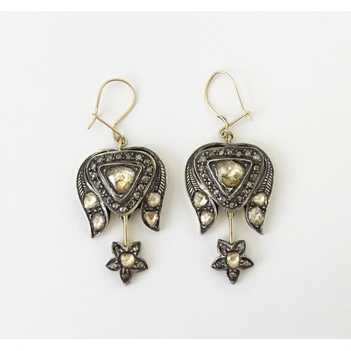 704 - A pair of yellower metal drop earrings set with a profusion of diamonds. Approx. 1 1/2