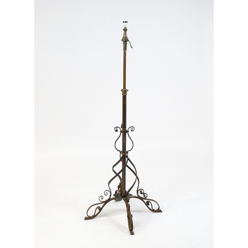 1553 - A c.1900 wrought iron standard lamp raised on four feet and decorated with wrought iron tendrils. Ma... 