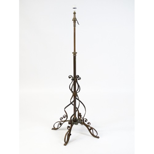 1553 - A c.1900 wrought iron standard lamp raised on four feet and decorated with wrought iron tendrils. Ma... 