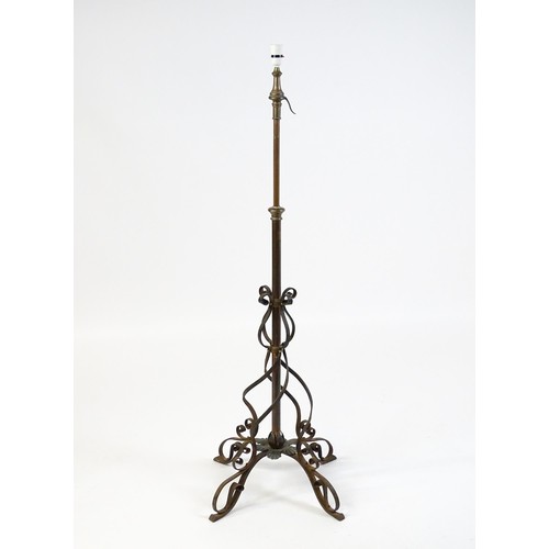 1553 - A c.1900 wrought iron standard lamp raised on four feet and decorated with wrought iron tendrils. Ma... 