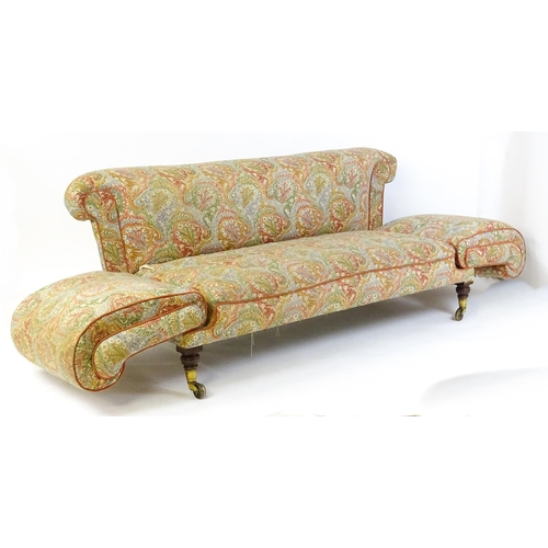 1564 - A Victorian sofa with two scrolled drop arms raised on mahogany legs terminating in large brass caps... 