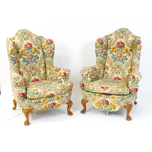 1585 - A pair of reproduction wingback armchairs with scrolled arms, and raised on cabriole legs with acant... 