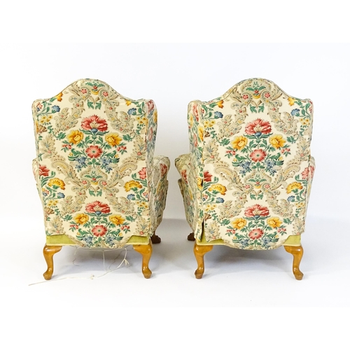 1585 - A pair of reproduction wingback armchairs with scrolled arms, and raised on cabriole legs with acant... 