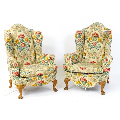 1585 - A pair of reproduction wingback armchairs with scrolled arms, and raised on cabriole legs with acant... 