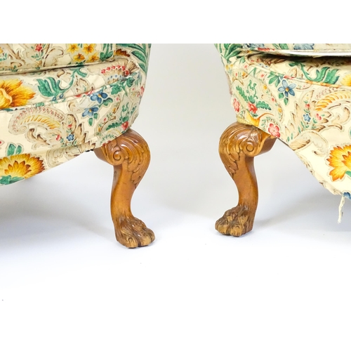 1585 - A pair of reproduction wingback armchairs with scrolled arms, and raised on cabriole legs with acant... 