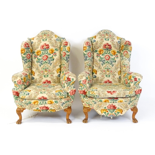 1585 - A pair of reproduction wingback armchairs with scrolled arms, and raised on cabriole legs with acant... 