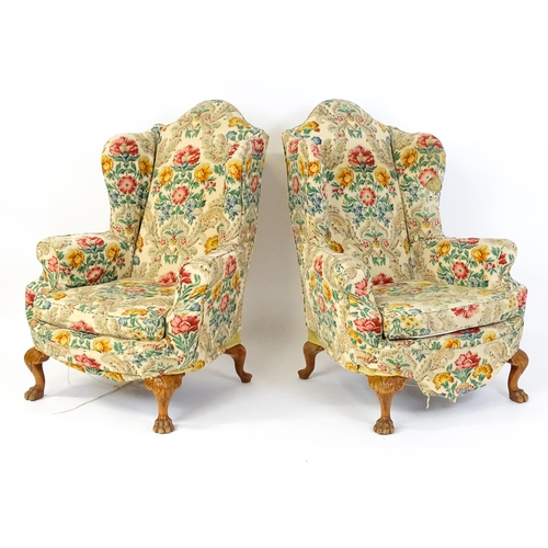 1585 - A pair of reproduction wingback armchairs with scrolled arms, and raised on cabriole legs with acant... 