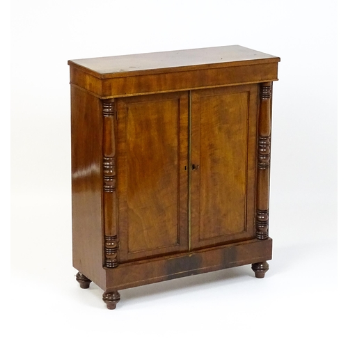 1599 - A 19thC mahogany cupboard with a rectangular top above two panelled doors flanked by turned tapering... 