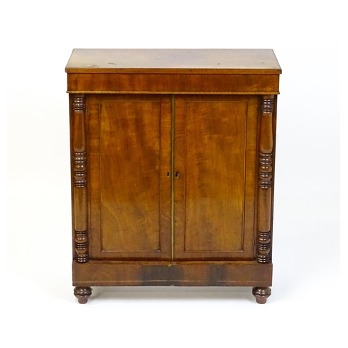 1599 - A 19thC mahogany cupboard with a rectangular top above two panelled doors flanked by turned tapering... 