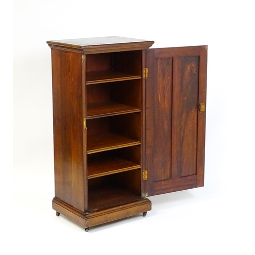 1618 - An early 20thC pine cabinet with a moulded top and panelled door concealing four shelves, the cabine... 