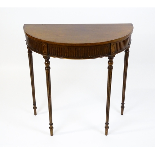 1630 - A 20thC mahogany demi-lune side table with a cross banded top, fluted frieze, and raised on four tur... 