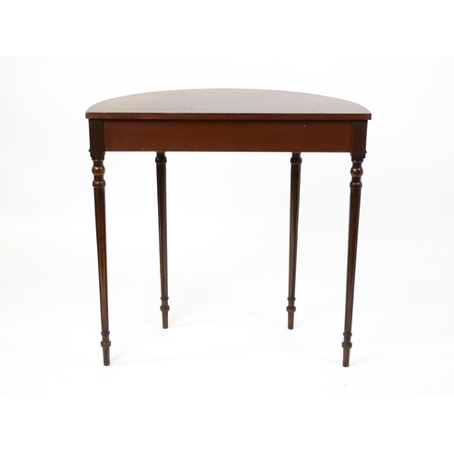 1630 - A 20thC mahogany demi-lune side table with a cross banded top, fluted frieze, and raised on four tur... 