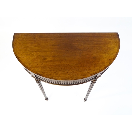 1630 - A 20thC mahogany demi-lune side table with a cross banded top, fluted frieze, and raised on four tur... 