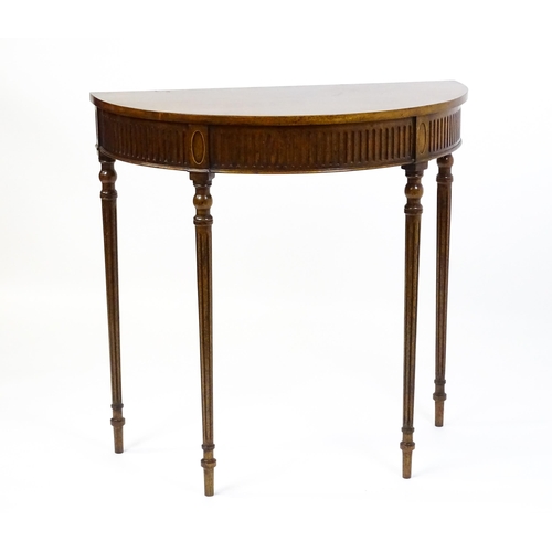 1630 - A 20thC mahogany demi-lune side table with a cross banded top, fluted frieze, and raised on four tur... 