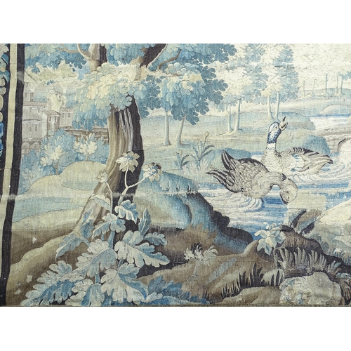 1383 - A late 17th / early 18thC Brussels tapestry depicting a pastoral tree lined landscape with castle by... 