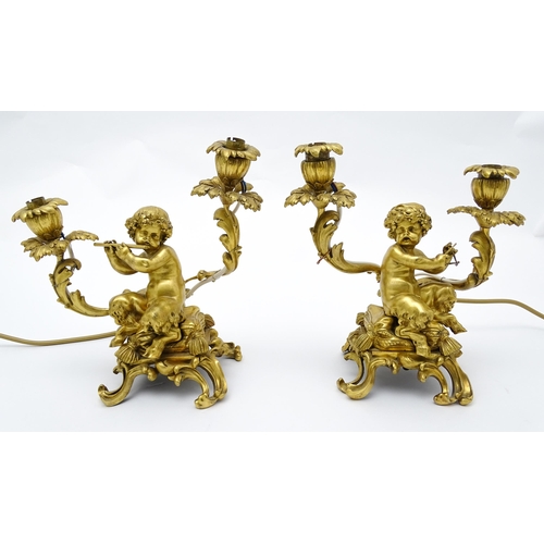 1532 - A pair of Continental gilt bronze twin branch table lamps, each modelled as a seated faun playing a ... 