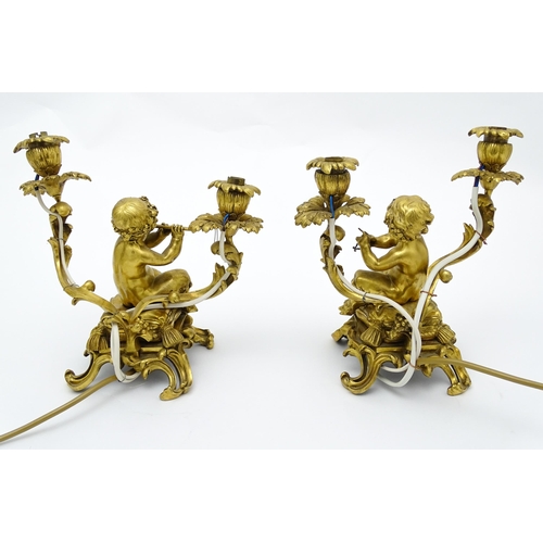 1532 - A pair of Continental gilt bronze twin branch table lamps, each modelled as a seated faun playing a ... 