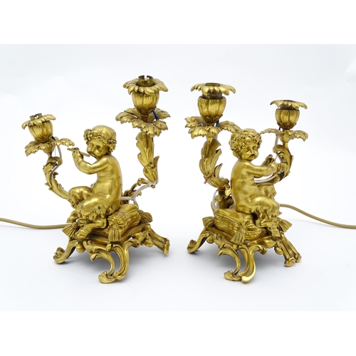 1532 - A pair of Continental gilt bronze twin branch table lamps, each modelled as a seated faun playing a ... 