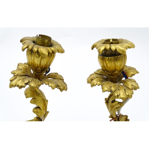 1532 - A pair of Continental gilt bronze twin branch table lamps, each modelled as a seated faun playing a ... 