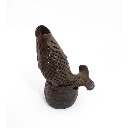 1020 - A Chinese bronze incense burner modelled as a fish on a stand decorated with crashing waves. Charact... 