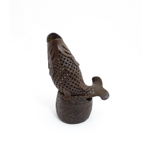 1020 - A Chinese bronze incense burner modelled as a fish on a stand decorated with crashing waves. Charact... 