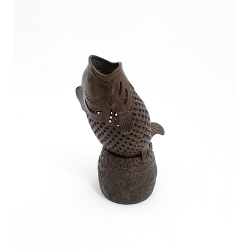 1020 - A Chinese bronze incense burner modelled as a fish on a stand decorated with crashing waves. Charact... 