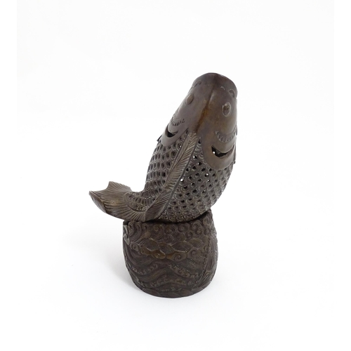 1020 - A Chinese bronze incense burner modelled as a fish on a stand decorated with crashing waves. Charact... 