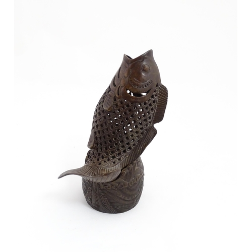 1020 - A Chinese bronze incense burner modelled as a fish on a stand decorated with crashing waves. Charact... 