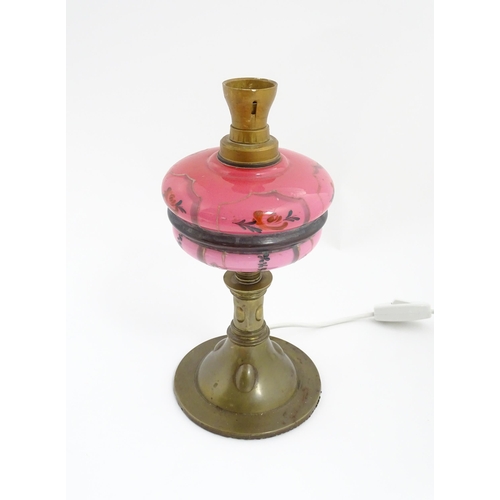 1536 - An Art & Crafts brass oil lamp with pink glass reservoir, converted to an electric table lamp. Appro... 