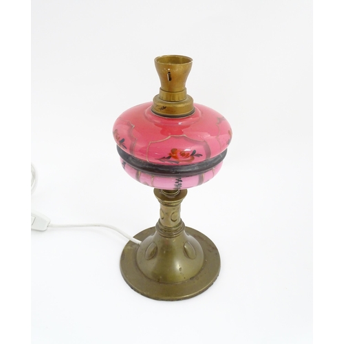 1536 - An Art & Crafts brass oil lamp with pink glass reservoir, converted to an electric table lamp. Appro... 