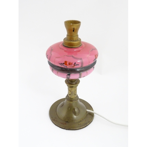 1536 - An Art & Crafts brass oil lamp with pink glass reservoir, converted to an electric table lamp. Appro... 